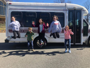 youth jumping in the air in front of bus