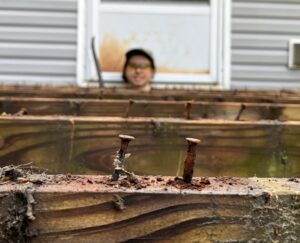 a head peeks out of a porch being demolished
